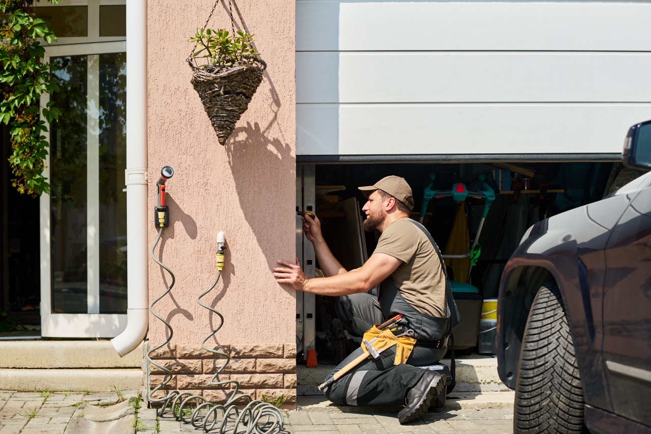 Professional Handyman Repairing a White Residential Garage Door